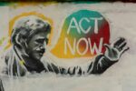 A striking mural featuring a figure with outstretched hand, accompanied by bold text that reads "ACT NOW" in vibrant colors.