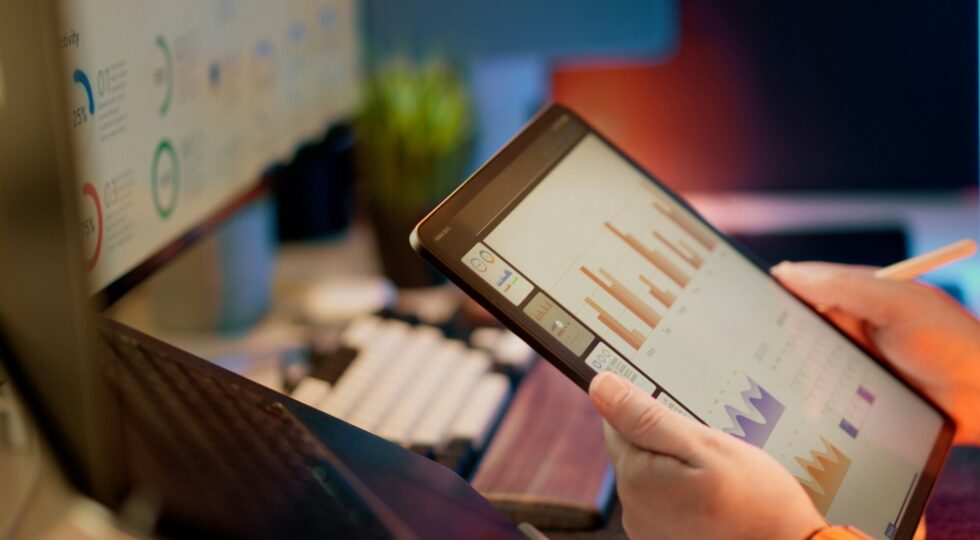 hands holding a tablet that has charts on its screen